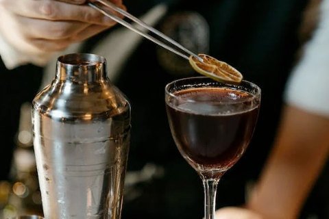 Closeup of a wedding bartender putting a lemon garnish on a cocktail, depicting the top quality of bartenders for weddings in Fredericskburg TX
