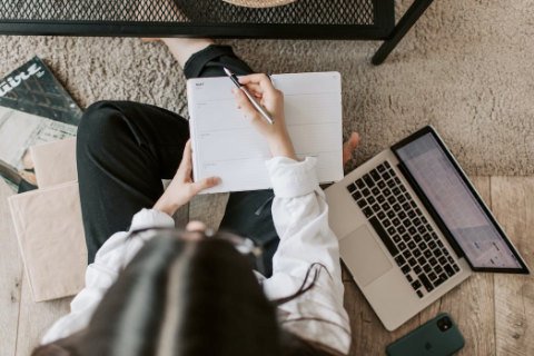 A female wedding planner sitting on the floor with a laptop and planner open in front of her, depicting the hard work Fredericksburg TX wedding planners put into all weddings in Fredericksburg TX