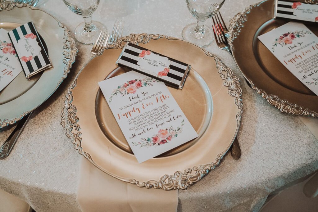 A gold wedding charger with a thank you card and wedding favor on top