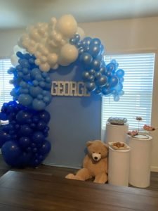A blue and white balloon arch for a baby shower celebrating a newborn named George. Decor provided by A Better Fete