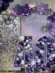 A 40 decor piece filled with purple, silver, and white balloons against a purple "Happy Birthday" backdrop, all provided by A Better Fete
