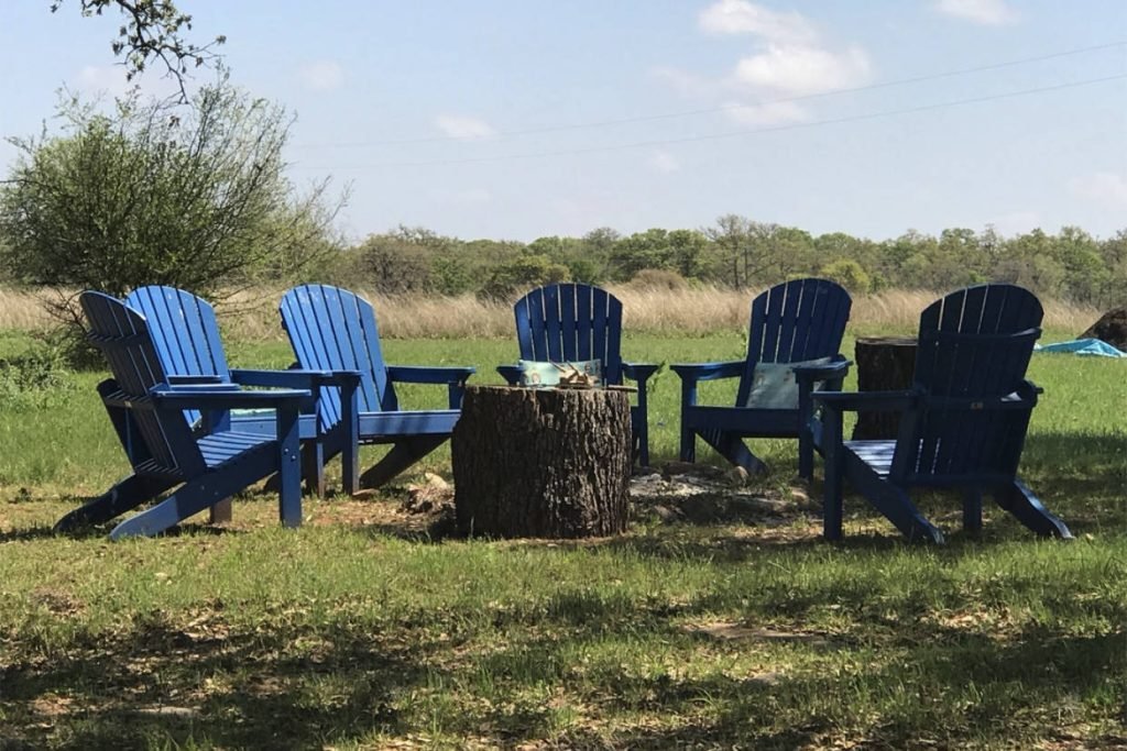 A circle of blue Adirondack chairs around a fire pit outside at The Venue & BnBs of Monarc Ranch