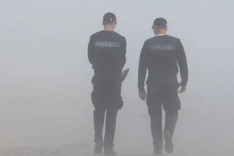 Two wedding security officers walking side by side through fog