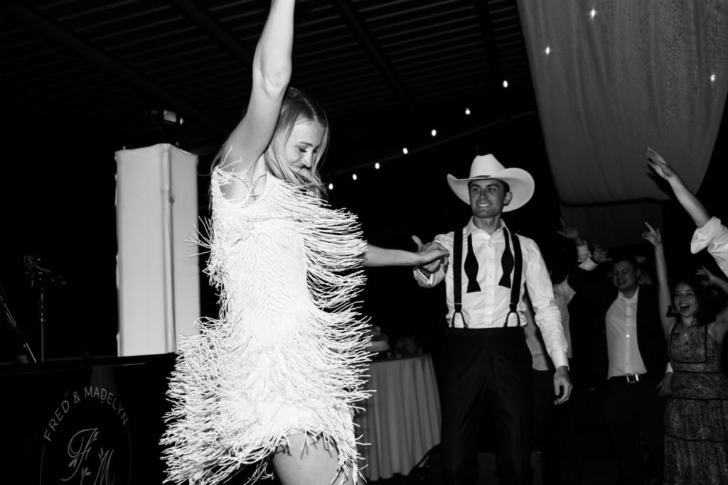 A bride in a fringe dress dancing with her cowboy husband, showing the fun that Gaines Entertainment provides at weddings in Fredericksburg TX