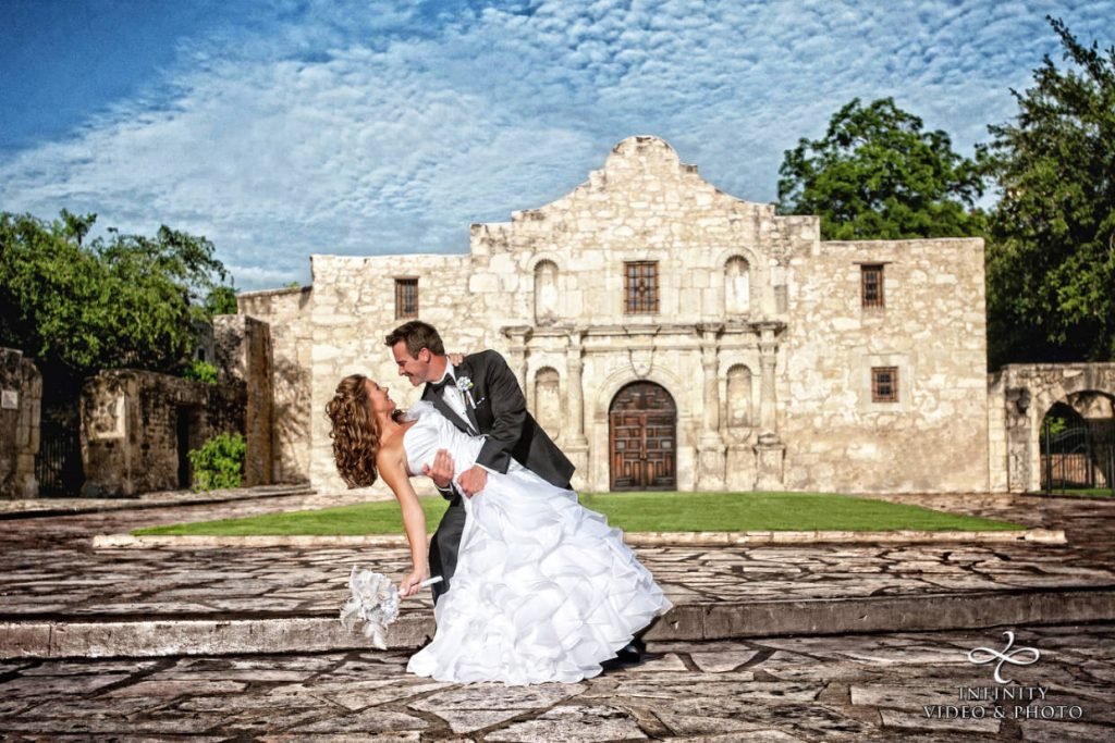 A bride and groom doing a dip in front of the San Antonio Alamo. Image captured by Infinity Video & Photo, a wedding videographer and photographer in Fredericksburg TX