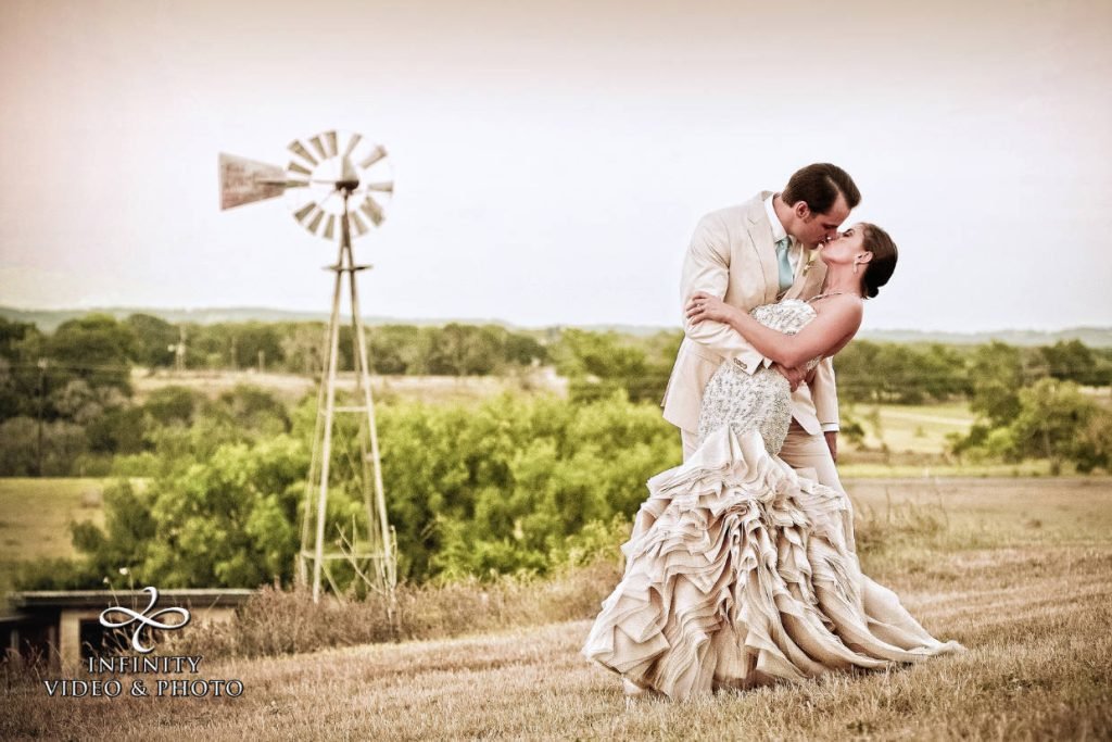 A bride and groom doing a slight dip kiss in a field. Image captured by Infinity Video & Photo, a wedding videographer and photographer in Fredericksburg TX