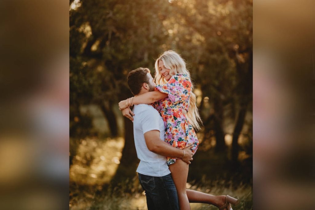 A man lifts his fiancee up as they dance in the sunset during golden hour. Image captured by Kayla Jane Photography, a wedding photographer in Fredericksburg TX