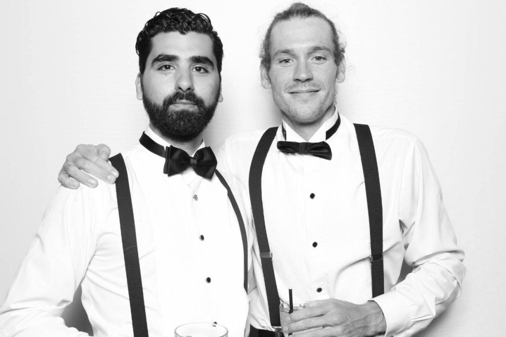 A black and white image of two groomsmen with their arms around each other at a wedding photo booth in Fredericksburg TX