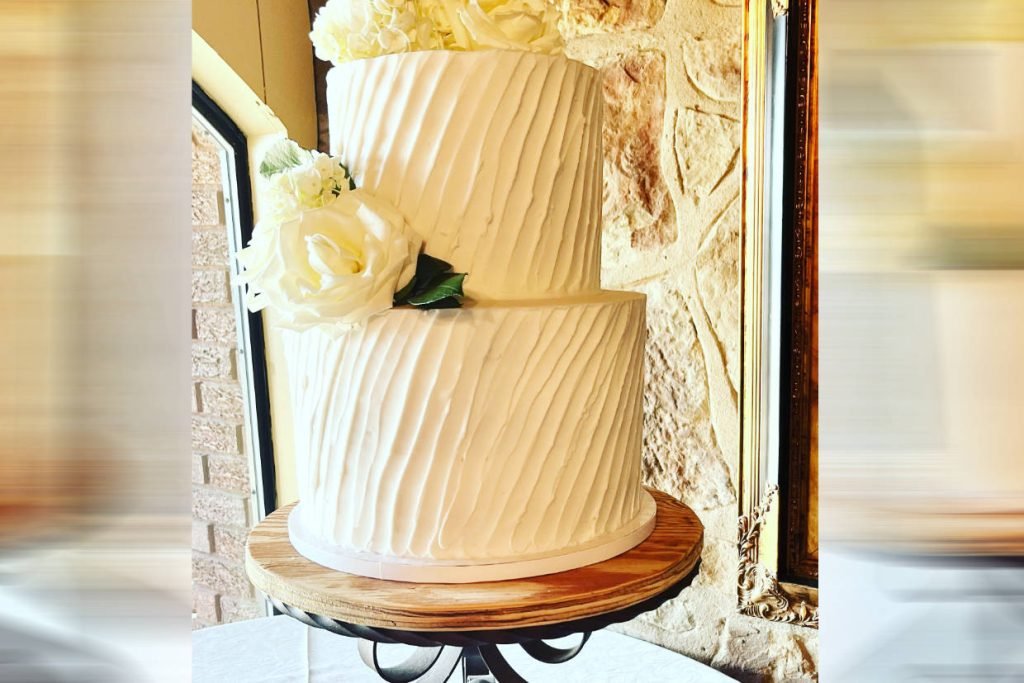 A closeup of a white 2-tier wedding cake, created by ROC Cakes and Cupcakes for weddings in Fredericksburg TX.