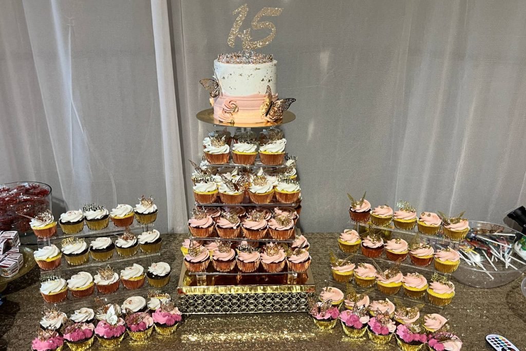 A one-tier cake with a "15" cake topper surrounded by cupcakes, all created by ROC Cakes and Cupcakes for weddings in Fredericksburg TX.