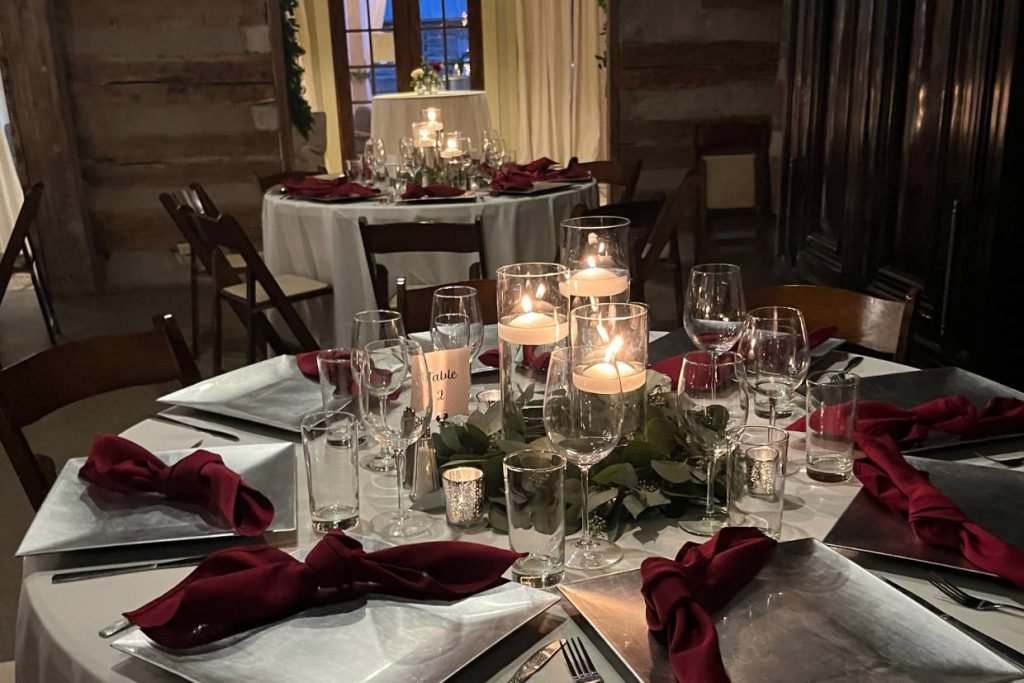 A closeup of a wedding reception table created by The Party Affair with red napkins and a trio of candles as the centerpiece
