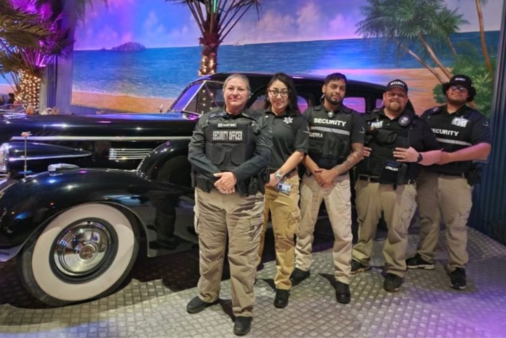 A group of male and female wedding security officers standing with a black classic car