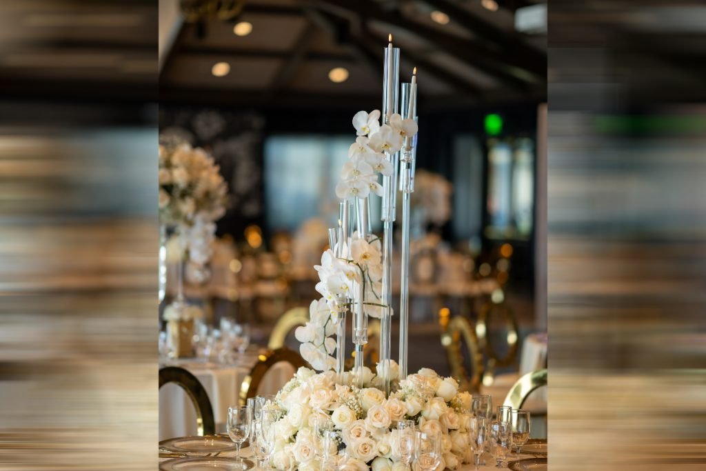 A cluster of skinny, taper candles in acrylic holders with white floral provided by Bisli Luxurious Events
